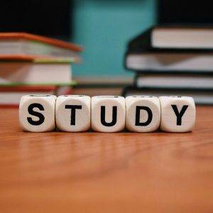 Close-up of study blocks and stacked books on a wooden desk, symbolizing education and learning.